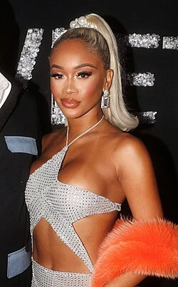 Saweetie wearing luminous spring outfits with juicy warm hues, showcasing papaya orange, sunny marigold, aqua turquoise, creamy ivory, and rose gold from the Warm Spring palette.